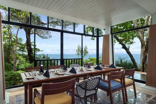 高兰Avani Plus Koh Lanta Krabi Resort的一间带桌椅和大窗户的用餐室