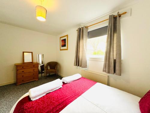 TillicoultryTillicoultry Jupiter Apartment - Scotland Holiday Let的一间卧室配有一张带红色毯子的床和窗户。