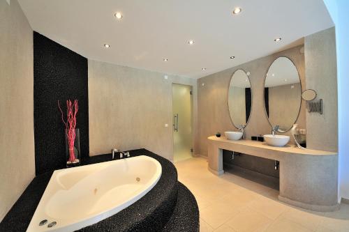 瓦西里亚斯Golden King Villas的浴室设有2个水槽、浴缸和2面镜子