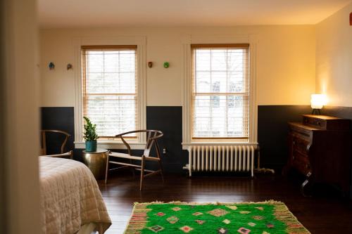 伍德斯托克The Vesper Woodstock的一间卧室配有一张床、一张桌子和两个窗户