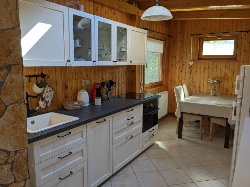 巴拉顿诺尔马迪Gabi háza的厨房配有白色橱柜、水槽和桌子