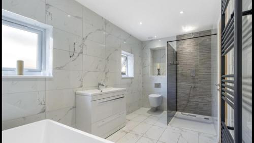 East BarnetNewly refurbished 3 bedroom property in north london的白色的浴室设有水槽和淋浴。