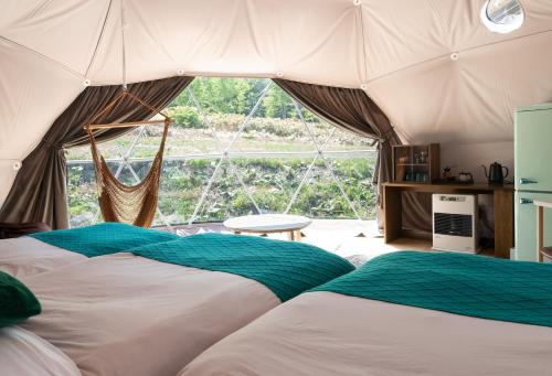 TomamuGlamping TOMAMU的帐篷内的两张床,设有大窗户