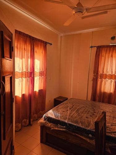 瓦加杜古Hébergement VIP的一间卧室配有橙色窗帘的床