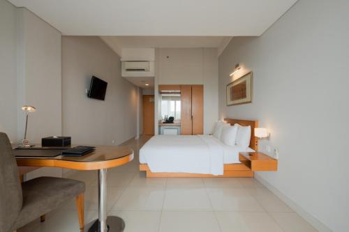 泗水The Capital Hotel Surabaya的卧室配有白色的床、书桌和书桌。