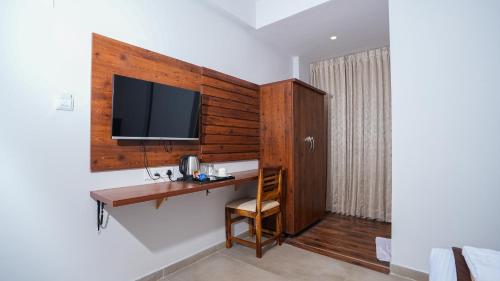 班加罗尔La Serene Business Hotel的客房设有书桌和墙上的电视