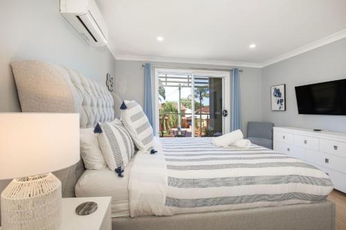 卡拉拉海滩Bluewater Jervis Bay - Pet Friendly with Spa的一间卧室配有一张床、一张沙发和一台电视