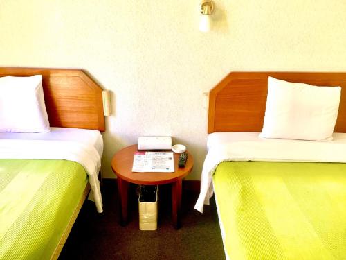 石垣岛Hotel Happy Holiday Ishigakijima - Vacation STAY 04133v的客房设有两张床和一张带电话的桌子。