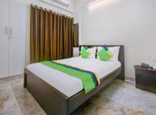 班加罗尔The Trinitywood Hotel & Restaurant的一间卧室配有一张带绿色枕头的大床