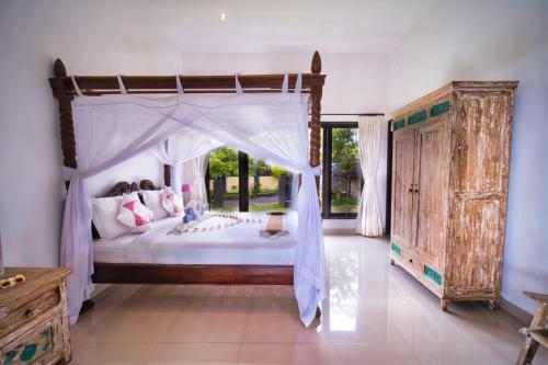 罗威那罗威那欣欣度假村的一间卧室设有一张天蓬床和大窗户