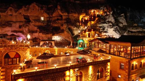 内夫谢希尔Cappadocia Nar Cave House & Swimming Pool的夜夜空在山前点亮的城市