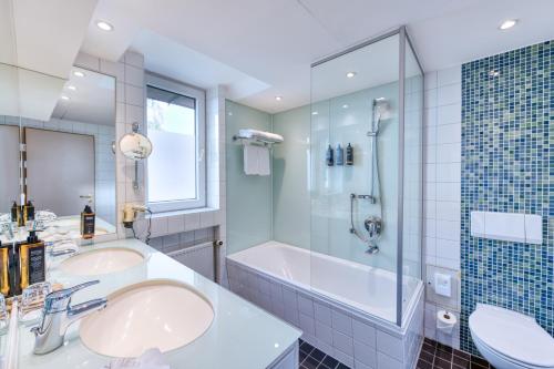 卡尔斯特杜塞尔多夫卡尔斯特美居酒店的浴室配有2个盥洗盆、浴缸和淋浴。