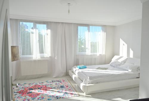 ArnavutköyAhmet teacher's villa, 6 minutes from the airport的一间白色卧室,配有两张床和地毯