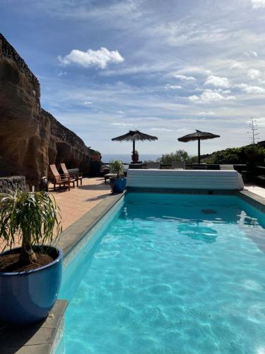 阿索马达Castillo Lanzarote Villa 3 - Sleep in a Volcanic Cave的一个带蓝色水和遮阳伞的游泳池