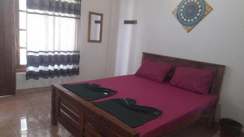 康提Suriya Villa的一间卧室配有一张带紫色床单和紫色枕头的床