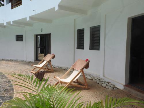 贝岛Auberge SAKATI'Art的两把木椅坐在建筑旁边的庭院里
