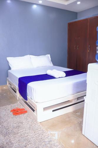 蒙巴萨Cathys Studio Apartment的蓝色墙壁的房间里一张白色的床