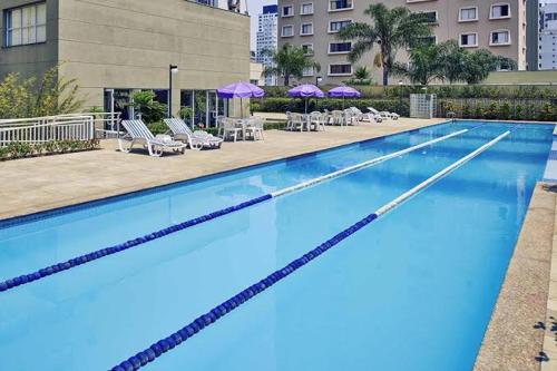 圣保罗M-Flat III Luxo - Hotel的一个带椅子和遮阳伞的大型游泳池