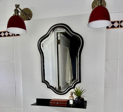 斯塔沃洛Gîte La Petite Francorchamps Ardennaise的墙上的镜子,有架子和两个灯