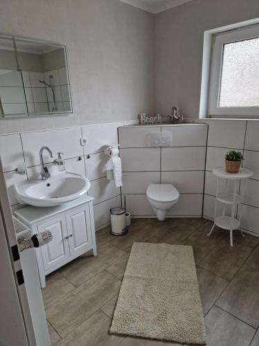 HageFerienwohnung Nordseetraum的一间带水槽、卫生间和镜子的浴室