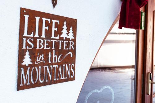 圣安东阿尔贝格Arlen Lodge Hotel的墙上的标志,上面写着:在山里生活更好