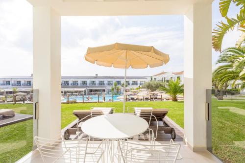 卡兰博希MarSenses Paradise Club的庭院配有白色的桌椅和遮阳伞。