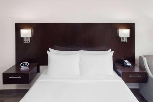墨尔本墨尔本戴斯酒店的一间卧室配有一张带白色床单的大床和2个床头柜