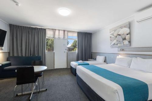 阿德莱德Comfort Inn Glenelg的酒店客房配有两张床和一张书桌