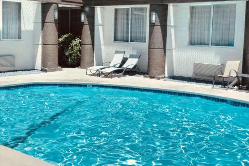 圣何塞乡村旅馆及套房卡尔森，圣何塞国际机场，加州的大楼前带两把椅子的大型游泳池