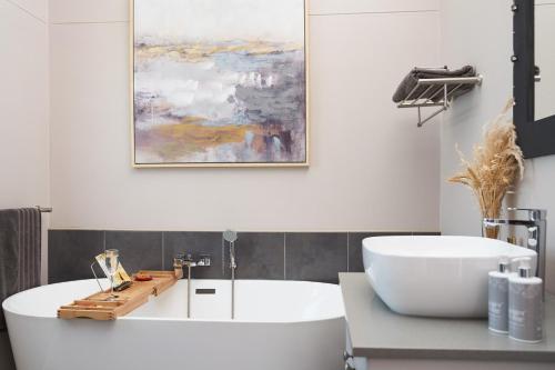 钦查HERON COTTAGE - for your seaside holiday.的浴室设有白色浴缸和墙上的绘画作品