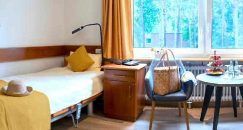 巴德贝芬森Heidehotel Bad Bevensen的卧室配有1张床、1张桌子和1把椅子