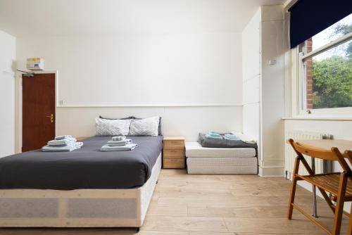 伦敦Large Studio on Finchley Road 10的一间卧室配有一张床、一张桌子和一个窗户。