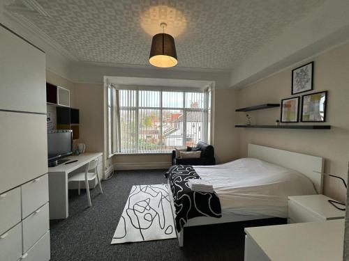 利物浦Abbeyfield Guesthouse的一间卧室配有一张床、一张书桌和一台电视