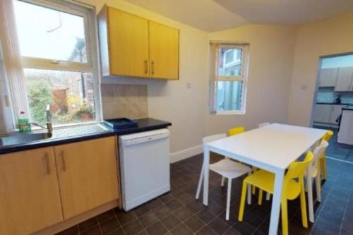 利物浦Abbeyfield Guesthouse的厨房配有白色的桌子和黄色的椅子