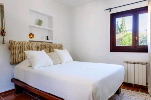 圣安东尼奥湾Authentic 4BR Pool & Sauna Villa, Sant Agusti的窗户客房内的一张白色床