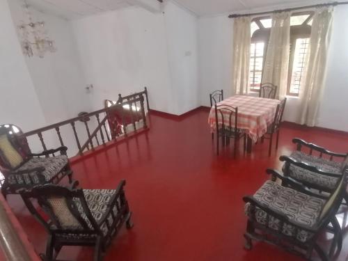 波隆纳鲁沃Sunshine Guest House的一间空房,配有椅子和一张桌子,铺有红色地板