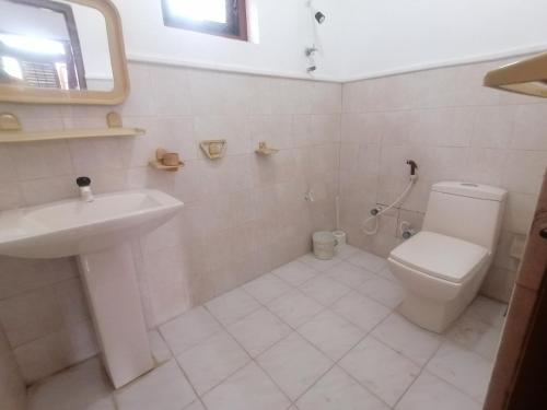 波隆纳鲁沃Sunshine Guest House的白色的浴室设有卫生间和水槽。