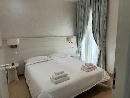 里米尼Marina Beach Aparthotel的卧室配有白色床和毛巾