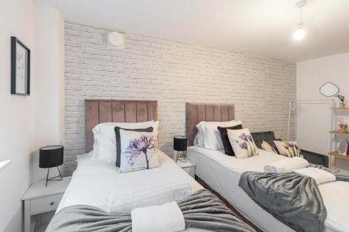 伦敦Tranquil Urban Haven的砖墙客房的两张床