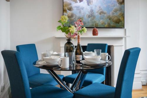 伦敦Modern Living in the Heart of Covent Garden! 6BC的用餐室配有蓝色椅子和一张带葡萄酒瓶的桌子