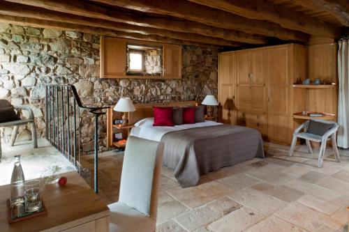 马西尼亚克HOTEL Domaine des Etangs, Auberge Resorts Collection的一间卧室设有一张床和石墙