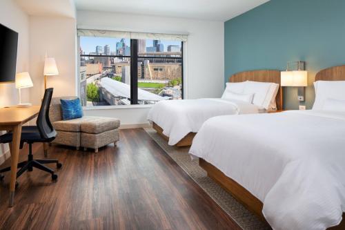 明尼阿波利斯Element Minneapolis Downtown North Loop的酒店客房设有两张床、一张书桌和一个窗户。