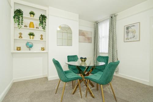 查塔姆Immaculate 3-Bed House in Chatham的一间设有玻璃桌和绿色椅子的用餐室