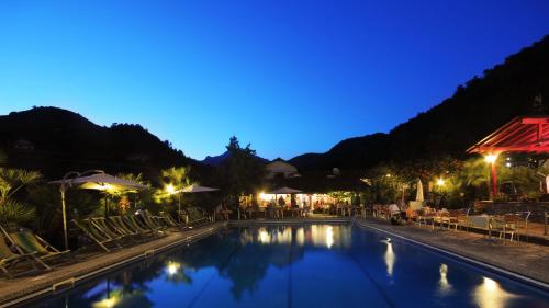 IsolabonaGlamping Italian Riviera的夜间游泳池,配有椅子和遮阳伞