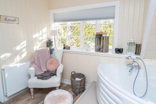 惠拉盖尔济SKYR Guest House的带浴缸、椅子和窗户的浴室
