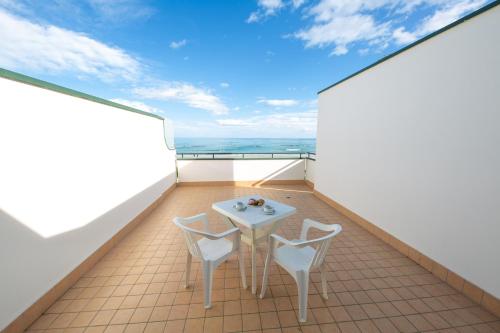 阿布鲁齐的罗塞托Hotel Roma Sul Mare的阳台配有桌子和两把椅子