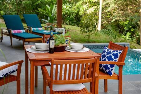 Benque Viejo del CarmenPrivate Modern Villa Near Resort District的一张带椅子的木桌和一瓶葡萄酒