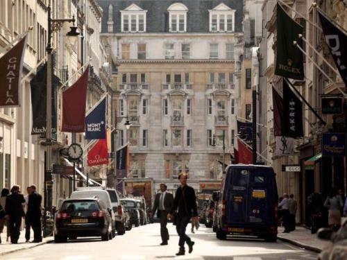 伦敦Bond Street Mayfair Penthouse的一条繁忙的城市街道,有汽车和人沿着街道走