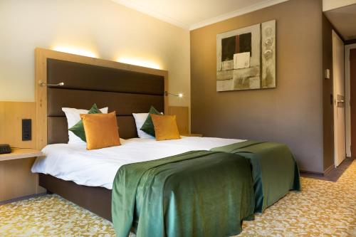 尼韦勒Hotel Restaurant Van Der Valk Nivelles-Sud的酒店客房配有一张带橙色和绿色枕头的大床。