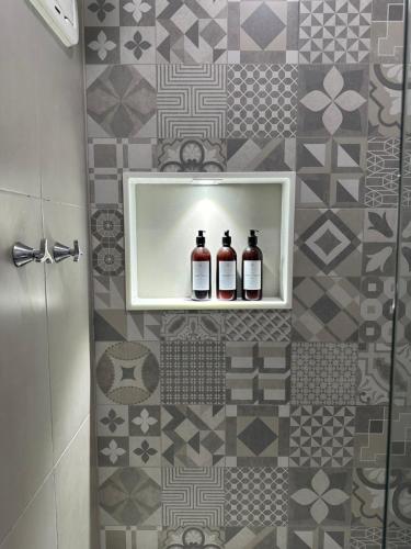 萨尔瓦多Apartamento Vista Mar aconchegante no Rio Vermelho的浴室的架子上摆放着两瓶葡萄酒